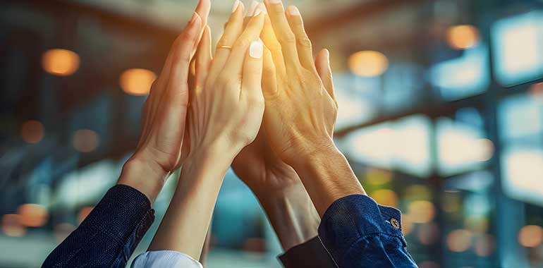 A group of professionals enthusiastically giving a high five, symbolizing successful collaboration on a PRM project in a modern office environment.